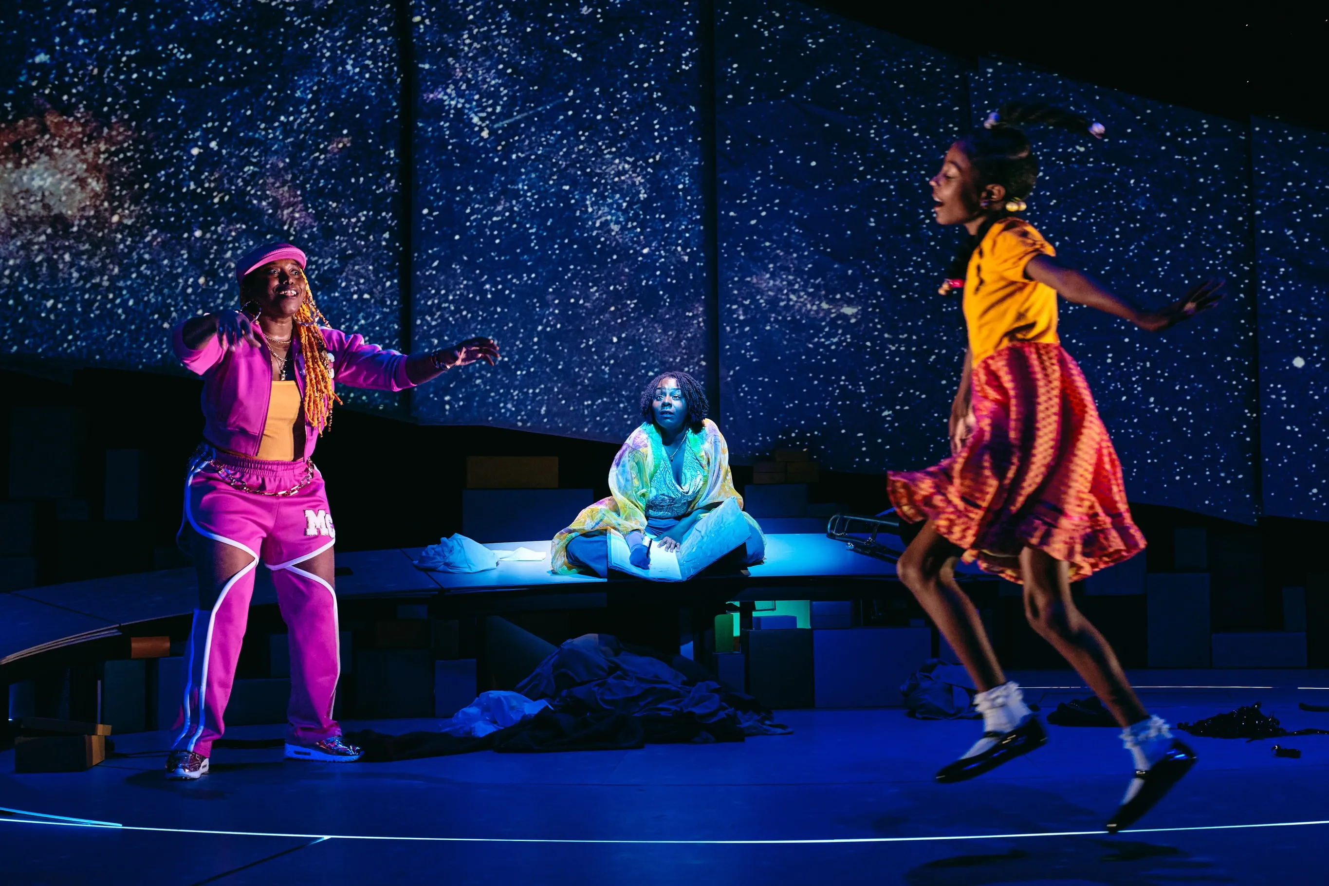 The company of Creation Stories on stage against a starfield
