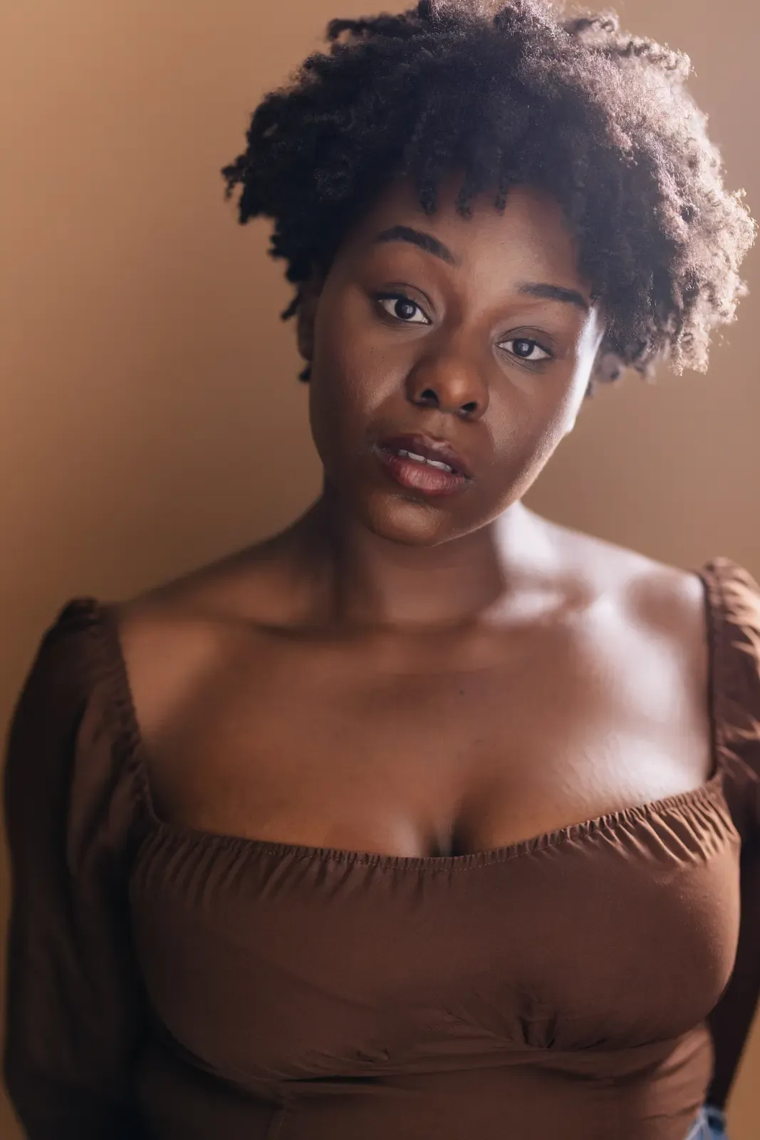 Abigail in a brown top against a warm brown background